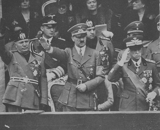 Vittorio Emanuele III, manifestamente corrucciato, saluta militarmente accanto ai due dittatori alla parata di Roma (maggio 1938). Alle spalle di Hitler Galeazzo Ciano.